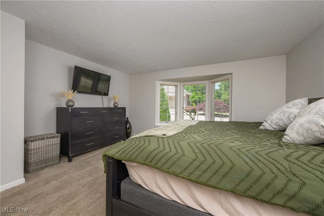 Bedroom featuring light carpet and a textured ceiling