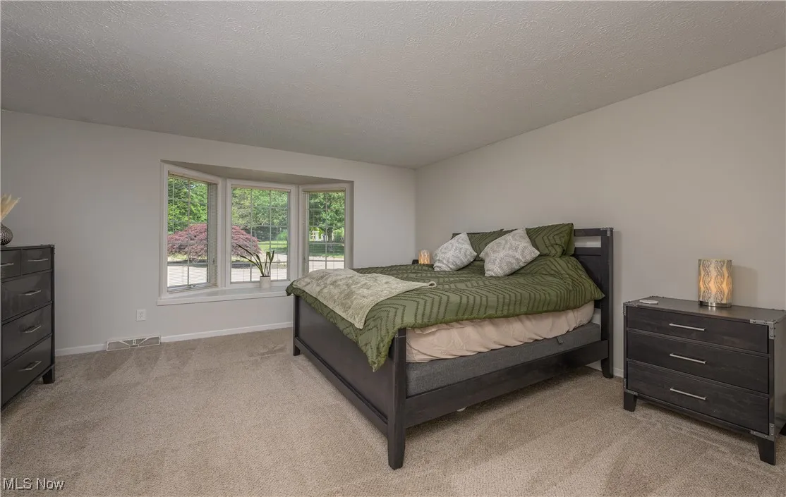 Bedroom with light colored carpet and baseboards