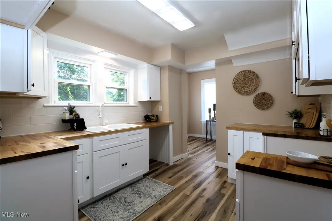 Kitchen featuring wood counters, backsplash, light wood-style floors, and white cabinetry