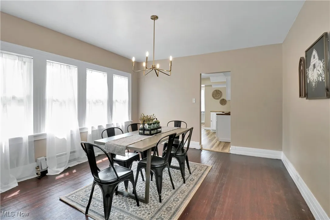 Dining space with a chandelier and dark wood-style flooring
