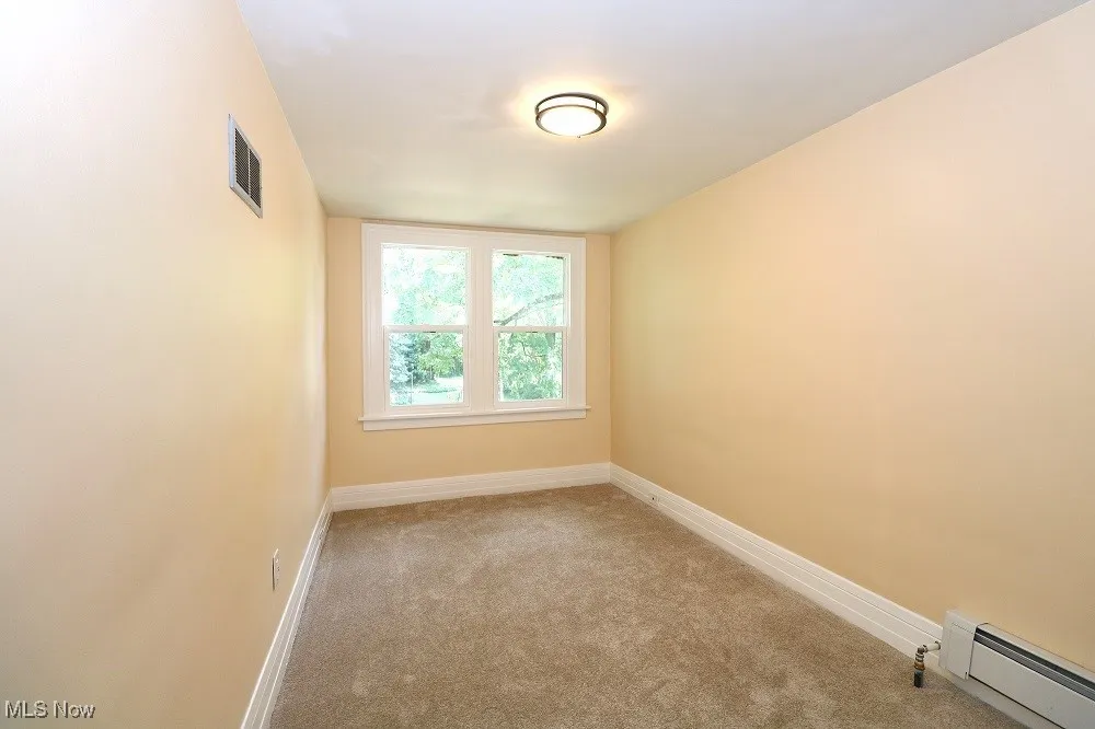 Carpeted spare room featuring baseboard heating and baseboards