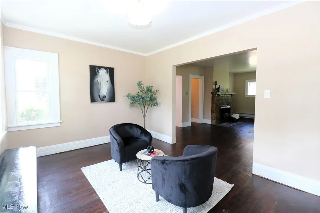 Sitting room featuring crown molding, dark wood finished floors, plenty of natural light, and a brick fireplace