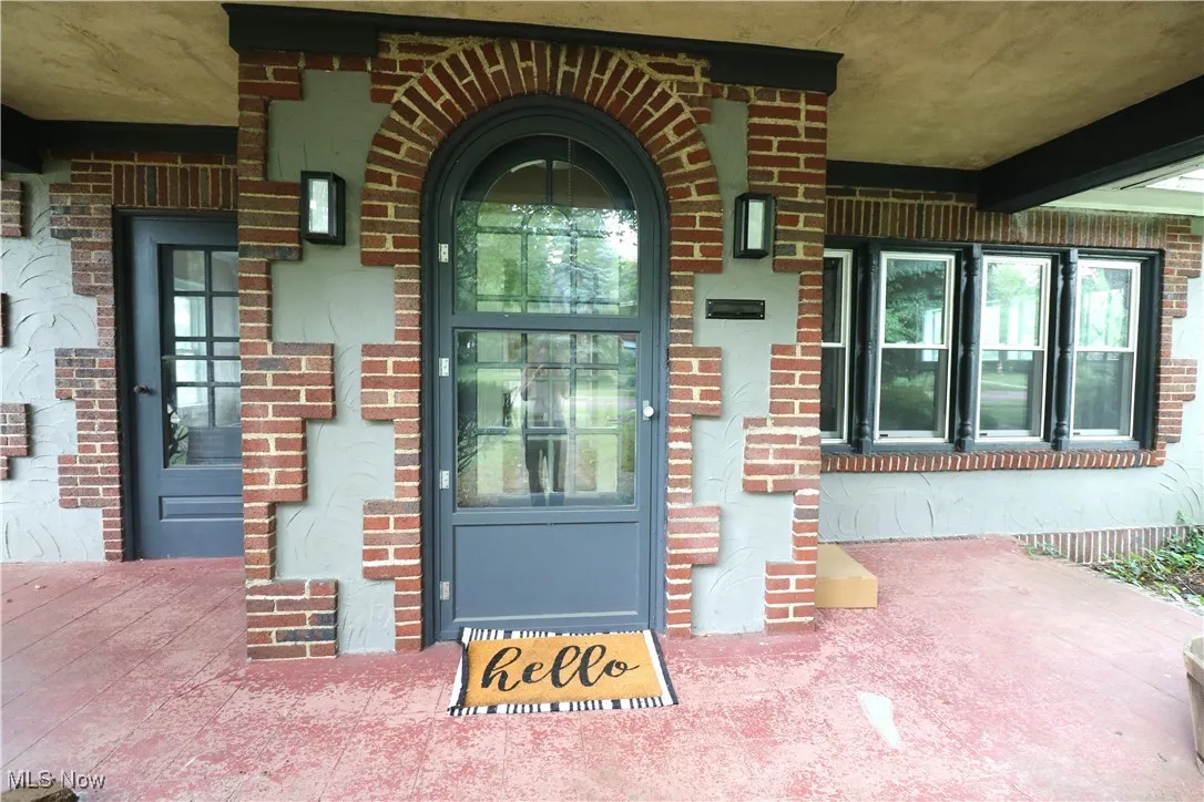 Entrance to property featuring brick siding and covered porch