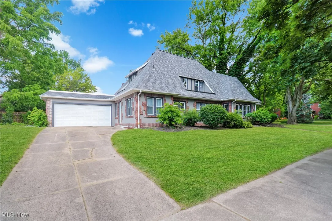 View of front of house with brick siding, concrete driveway, roof with shingles, and a front lawn