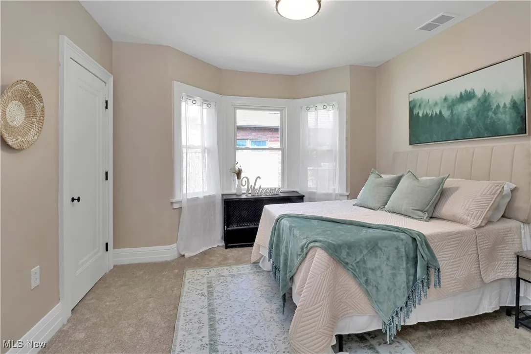 Bedroom with light colored carpet and baseboards