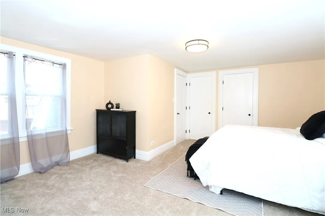 Bedroom featuring light carpet and two closets