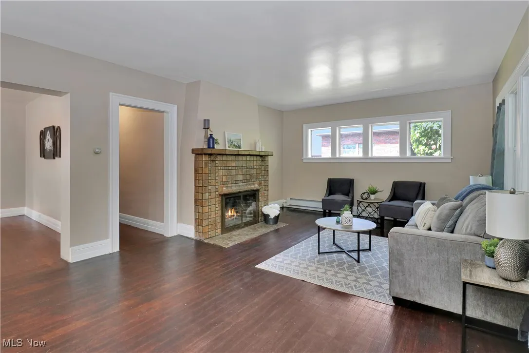 Living room with wood finished floors, a baseboard radiator, and a fireplace