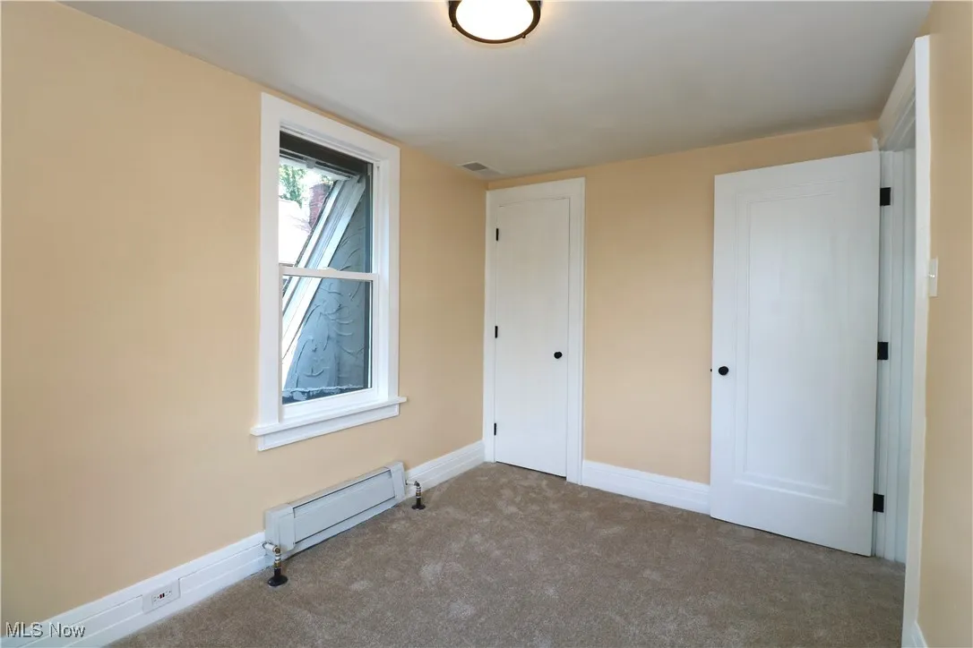 Unfurnished bedroom with baseboard heating and carpet floors