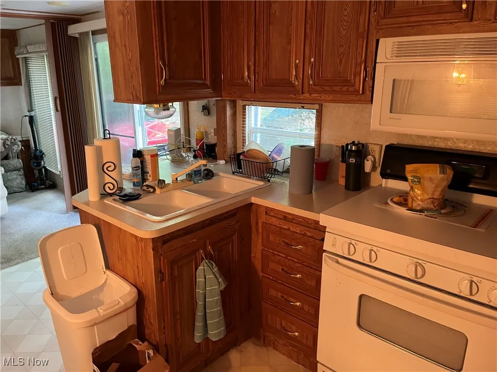 Kitchen featuring white appliances, light countertops, and a peninsula