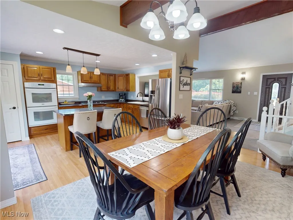 Dining space featuring a chandelier, plenty of natural light, light wood-style floors, beam ceiling, and recessed lighting