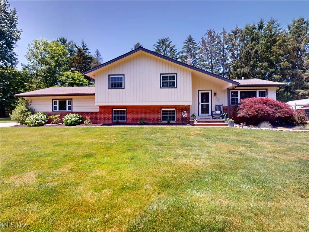 Tri-level home with a front lawn and brick siding