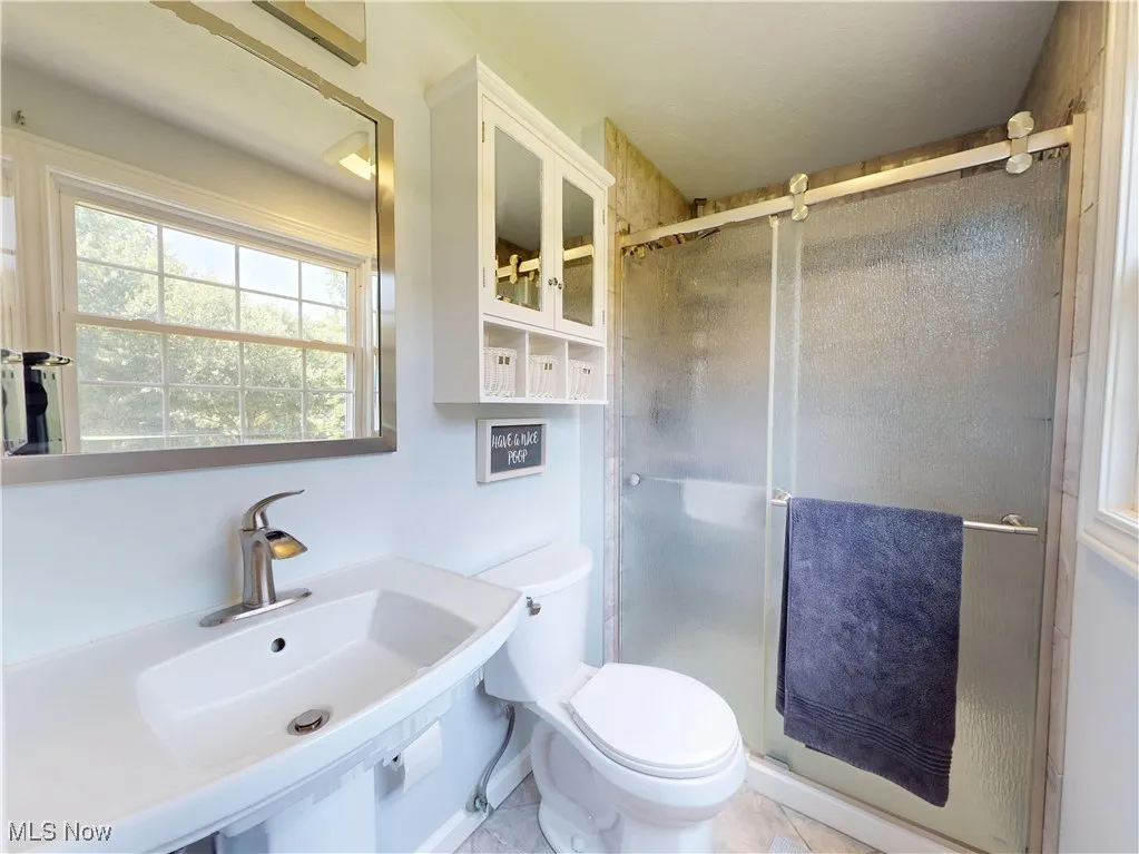 Full bathroom featuring a shower stall and tile patterned flooring