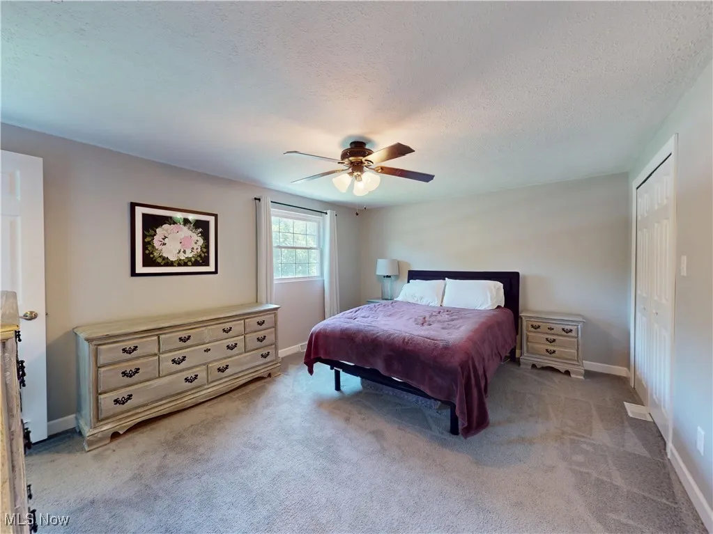 Bedroom with carpet floors, a textured ceiling, ceiling fan, and a closet
