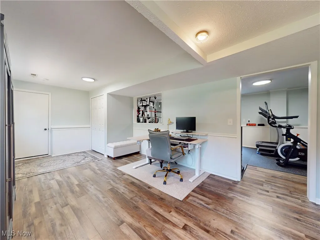 Home office featuring a wainscoted wall and wood finished floors
