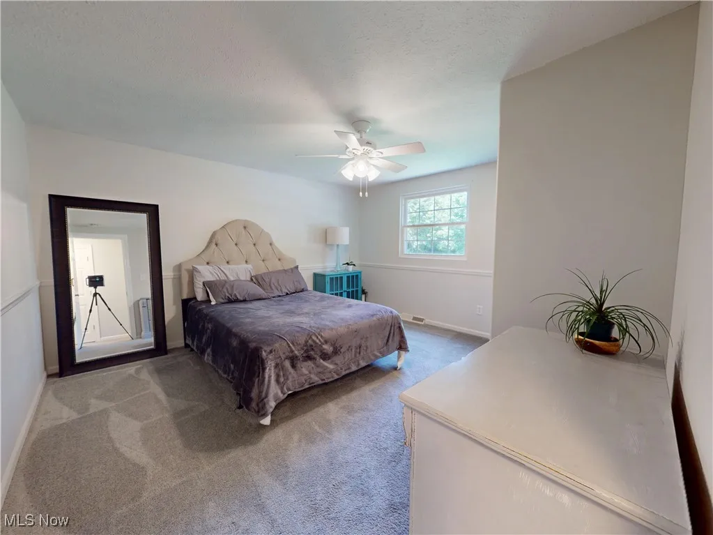 Bedroom featuring carpet floors, ceiling fan, and a textured ceiling
