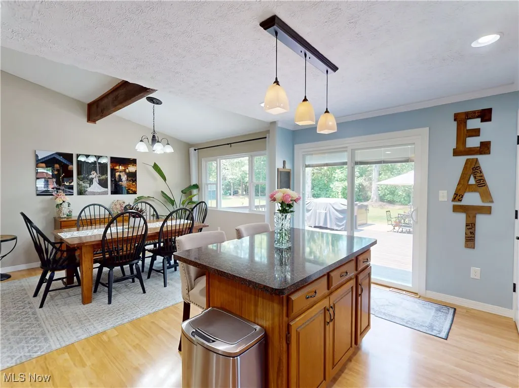 Kitchen featuring brown cabinetry, light wood-style flooring, a textured ceiling, healthy amount of natural light, and decorative light fixtures