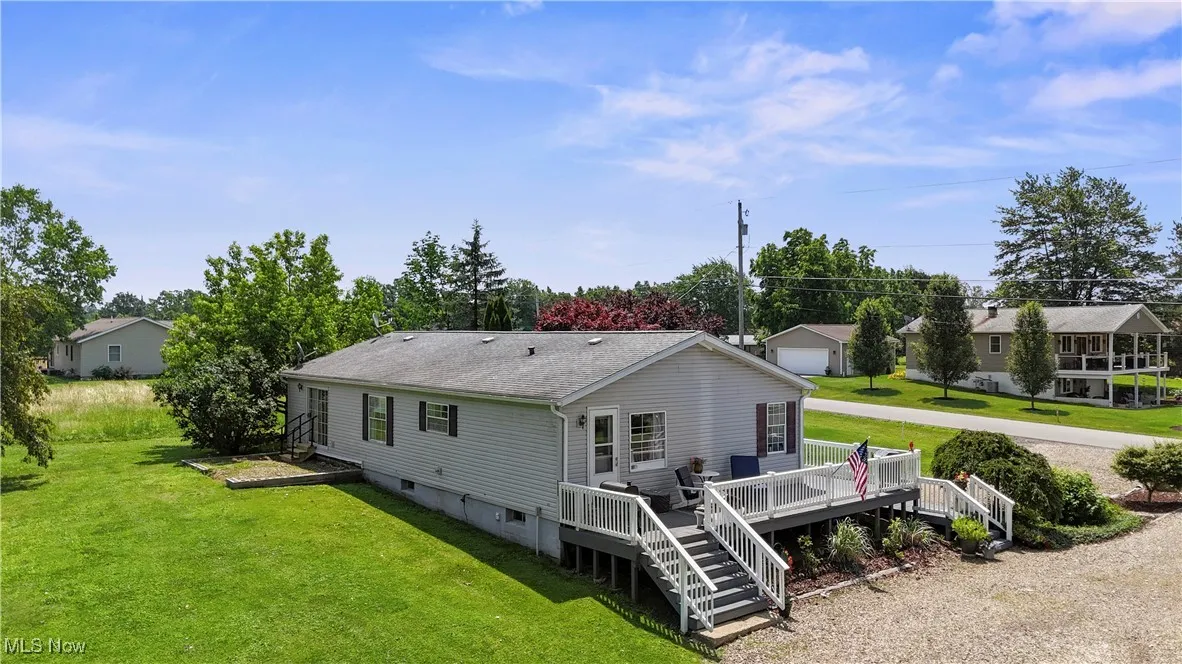 Back of house featuring a wooden deck, a yard, stairway, and a shingled roof