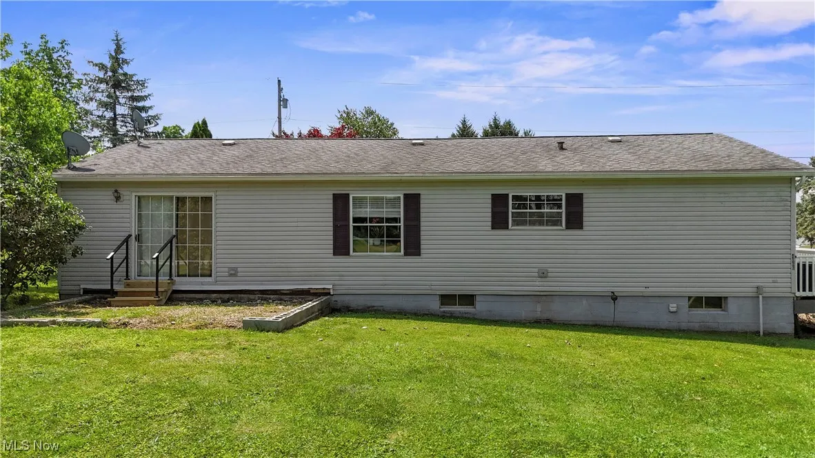 Rear view of property with a lawn and roof with shingles