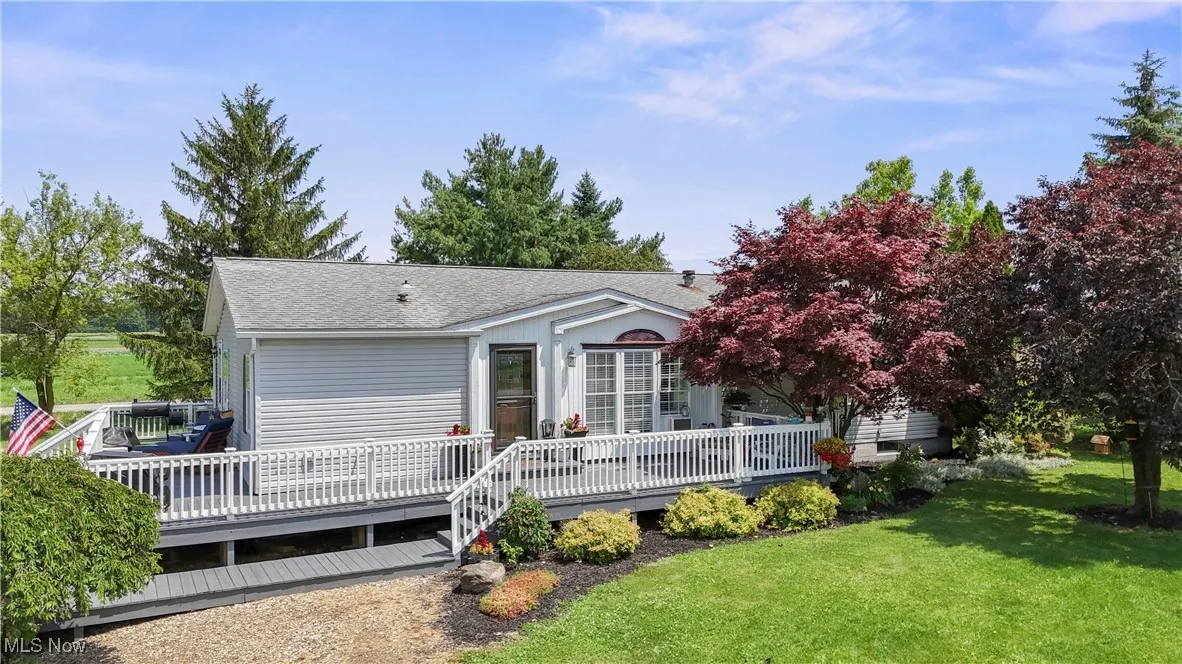 Back of property with a lawn, a shingled roof, and a deck