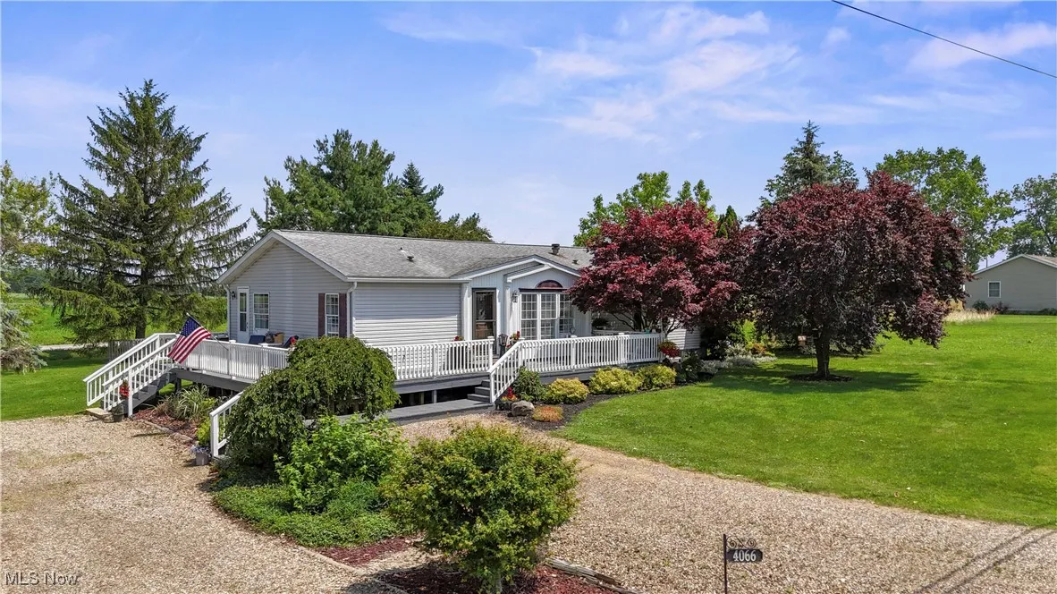 View of front of home with a front yard, a deck, and roof with shingles