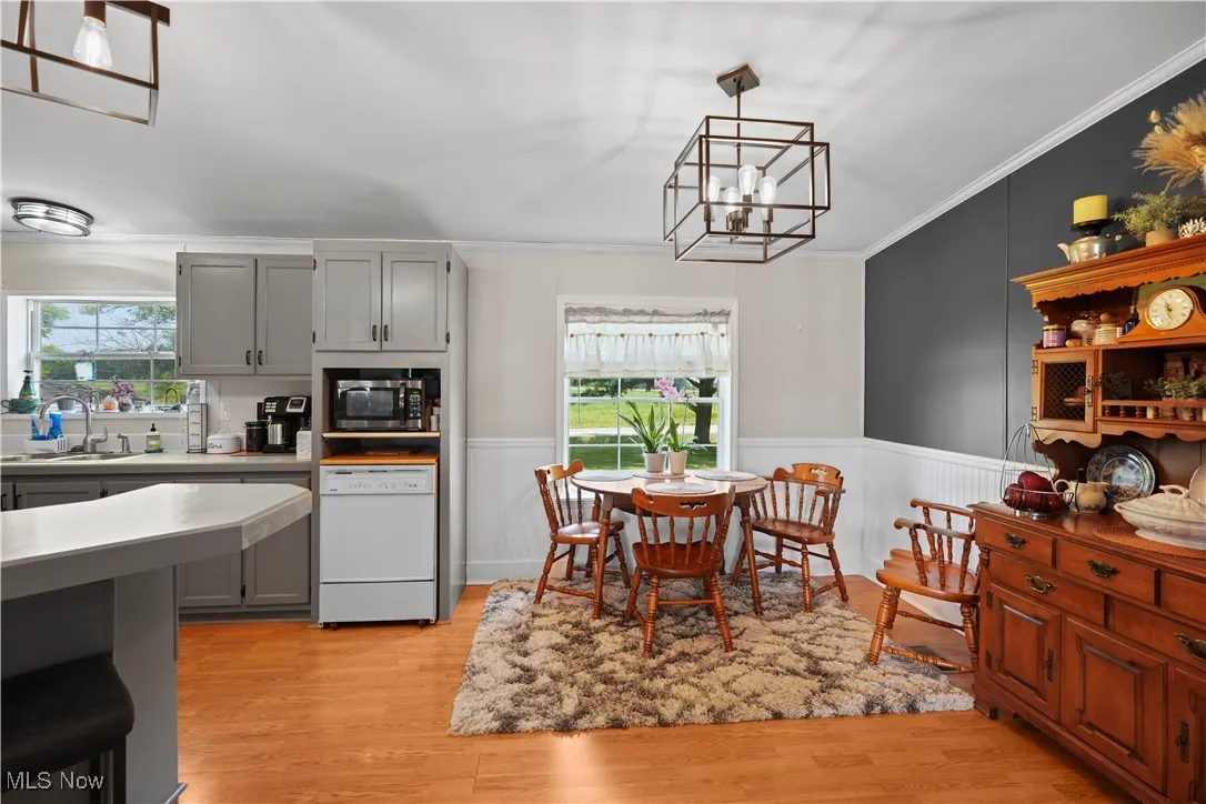Kitchen featuring dishwasher, gray cabinets, a chandelier, healthy amount of natural light, and ornamental molding
