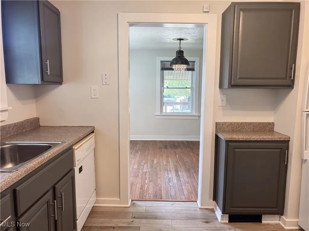 Kitchen featuring dishwasher, hardwood / wood-style floors, a chandelier, and gray cabinets