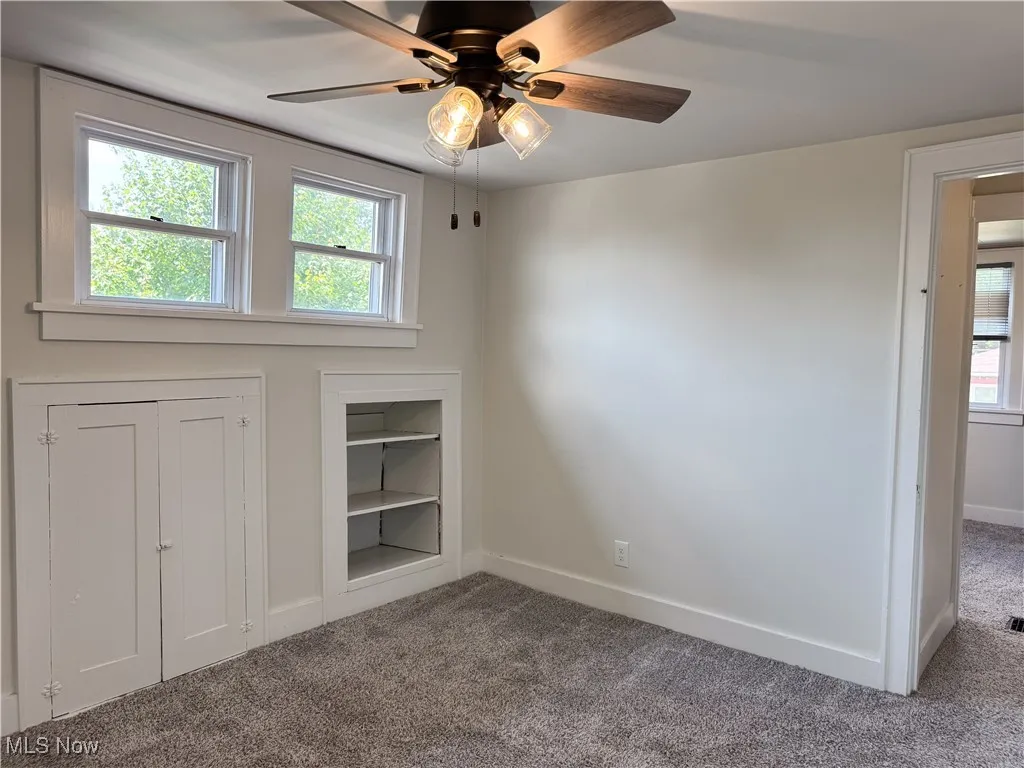 Bedroom featuring carpet flooring, ceiling fan, and built in shelves