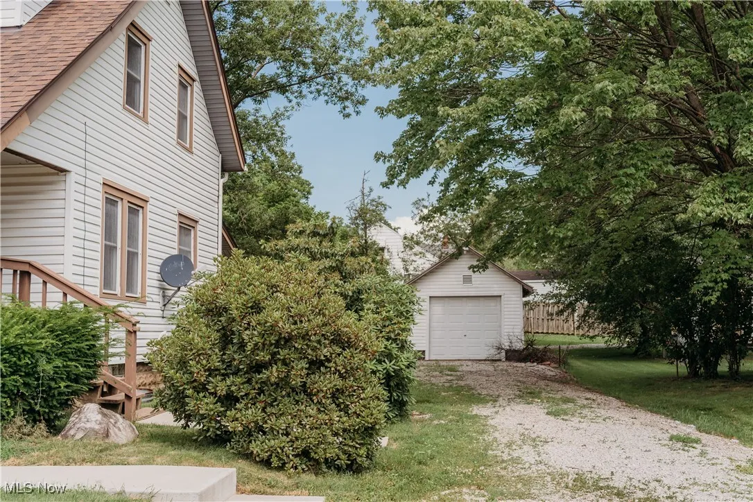 View of home's exterior with gravel driveway, an a shingled roof, and a garage
