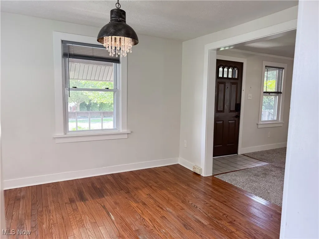 Dining room with healthy amount of natural light, wood finished floors, and a chandelier