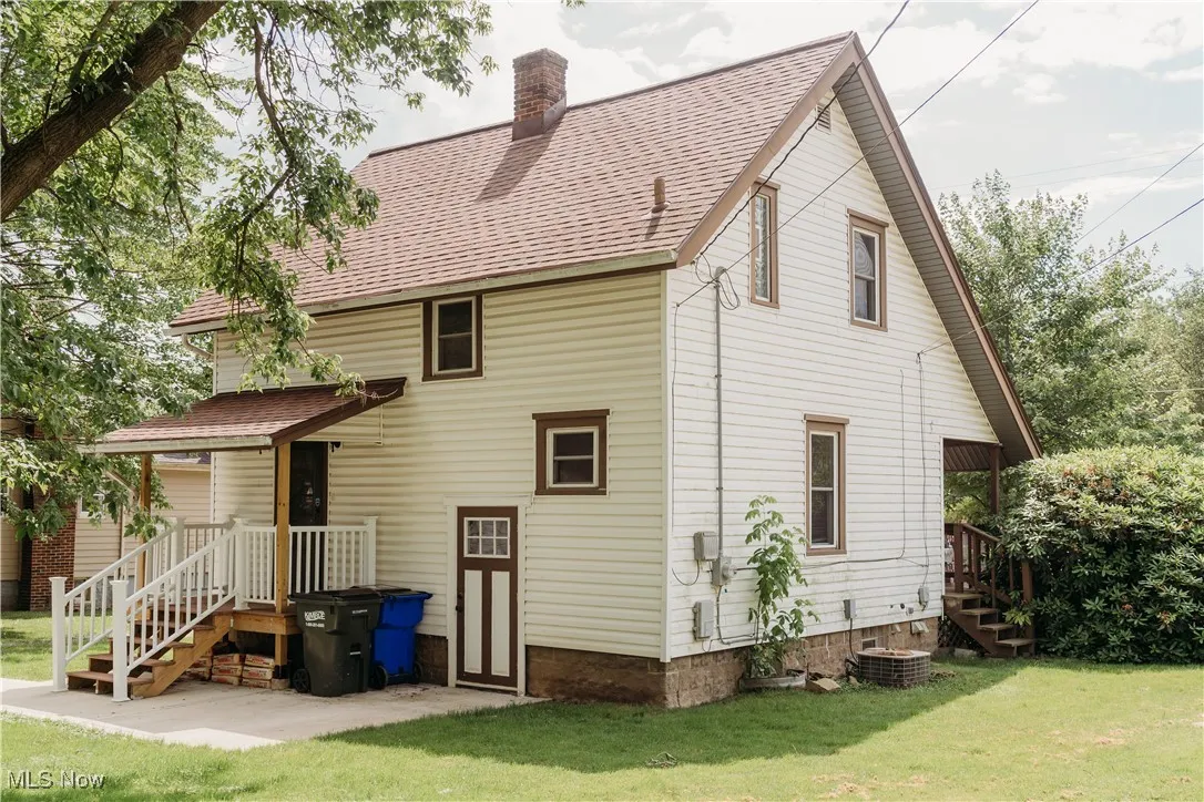 Rear view of house with a lawn, a chimney, and roof with shingles