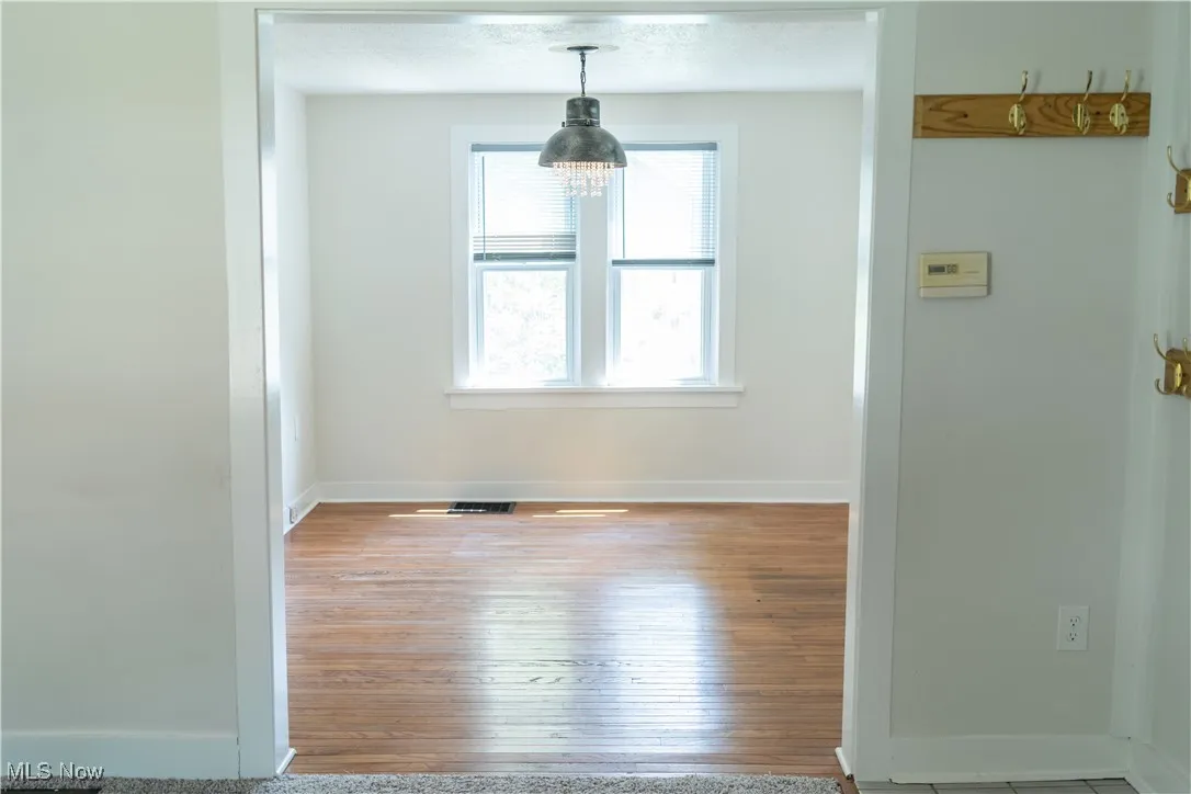 Unfurnished dining area with wood  floors and a chandelier