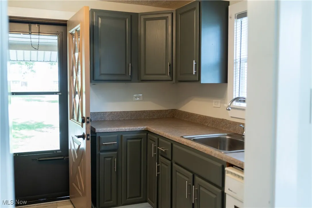 Kitchen featuring healthy amount of natural light, white dishwasher, and gray cabinets