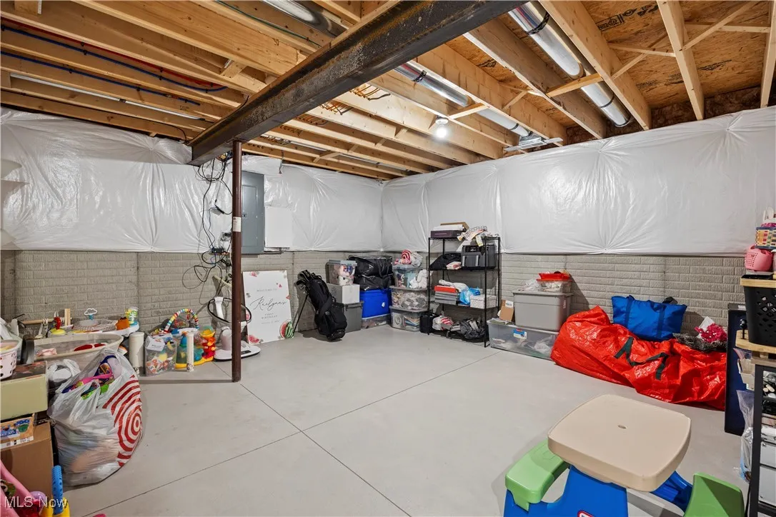 Storage area of basement with electric breaker panel and rough in for a downstairs bathroom