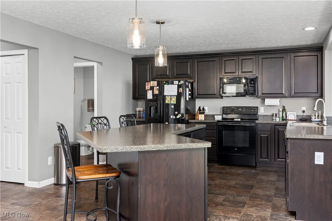 Kitchen with black appliances, breakfast bar, kitchen island, and a peninsula