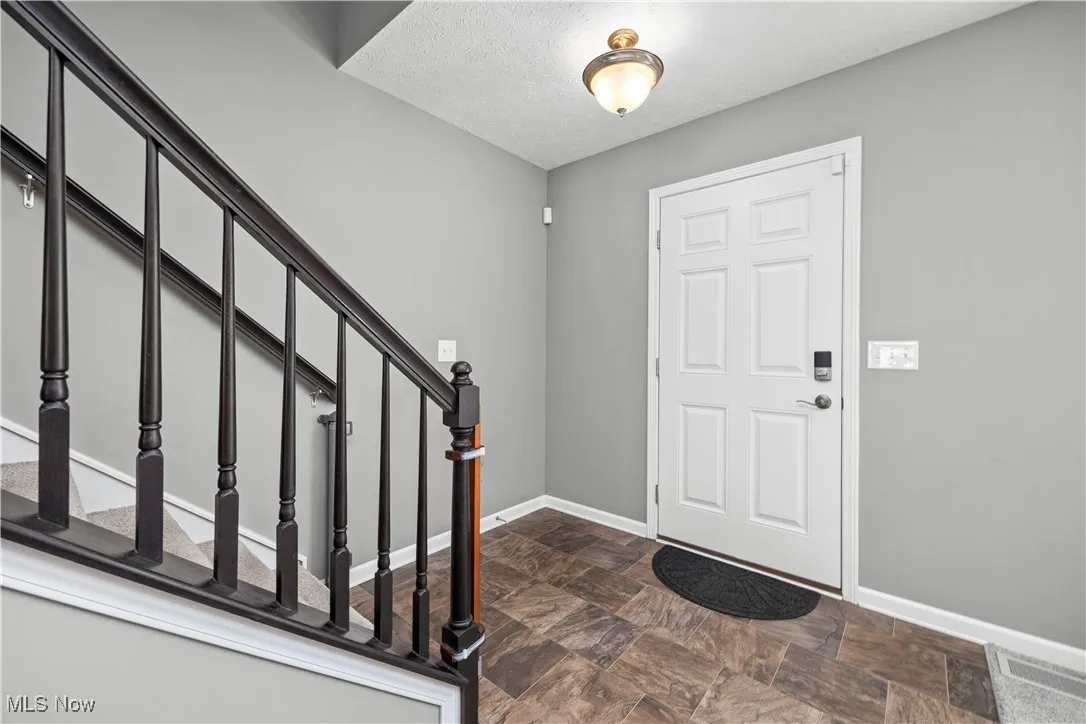 Foyer with vinyl flooring, dark handrails for stairway, and good lighting