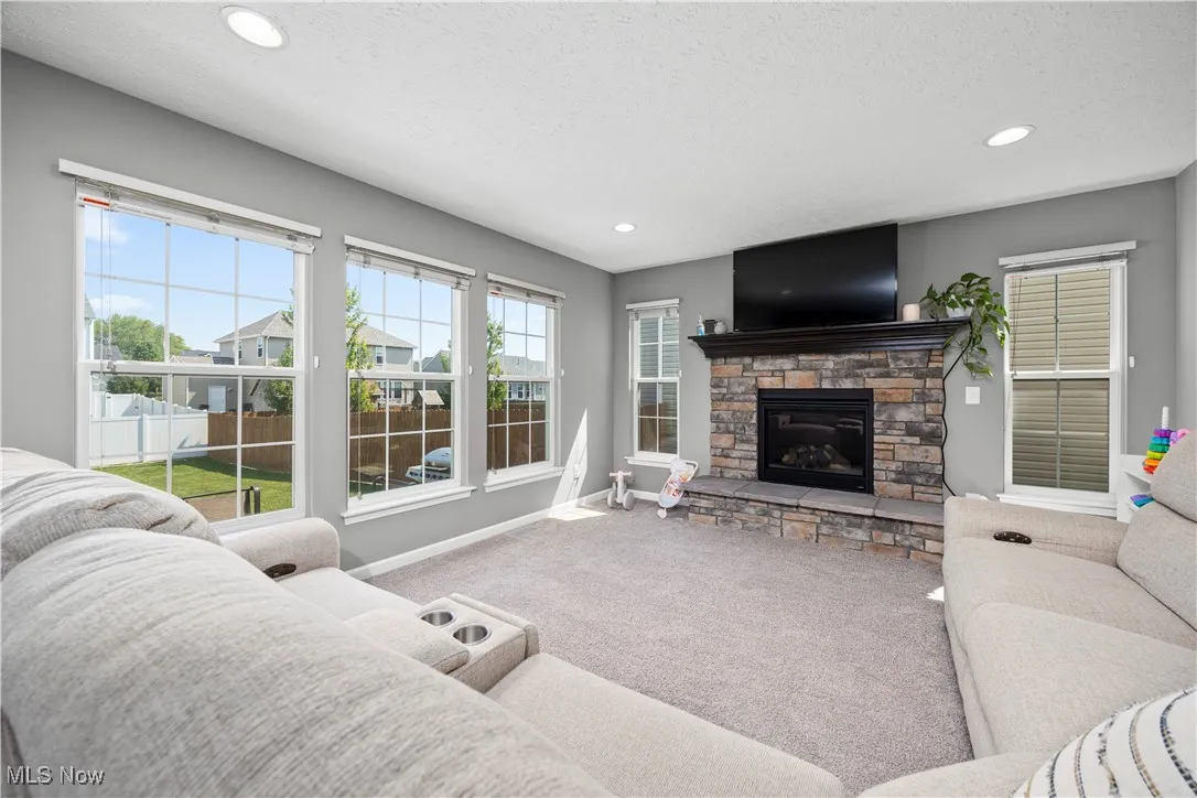 Living room area, loads of natural lighting, a stone faced gas log fireplace,