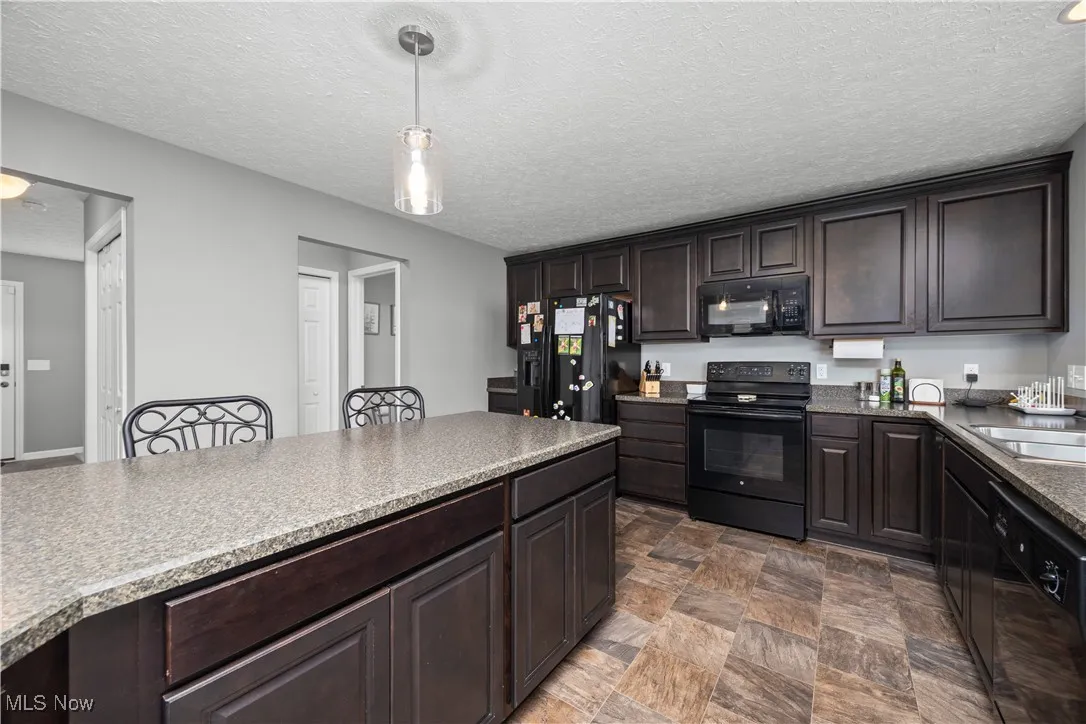 Kitchen with black appliances, breakfast bar, kitchen island, and a peninsula