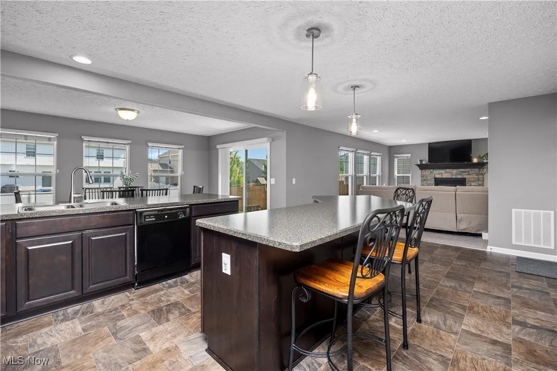 Kitchen with black appliances, breakfast bar, kitchen island, and a peninsula with another eating area view faces away from stove towards living room and morning room and or dining area