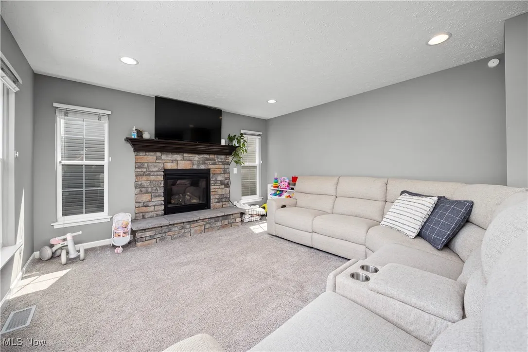 Living room area, loads of natural lighting, a stone faced gas log fireplace