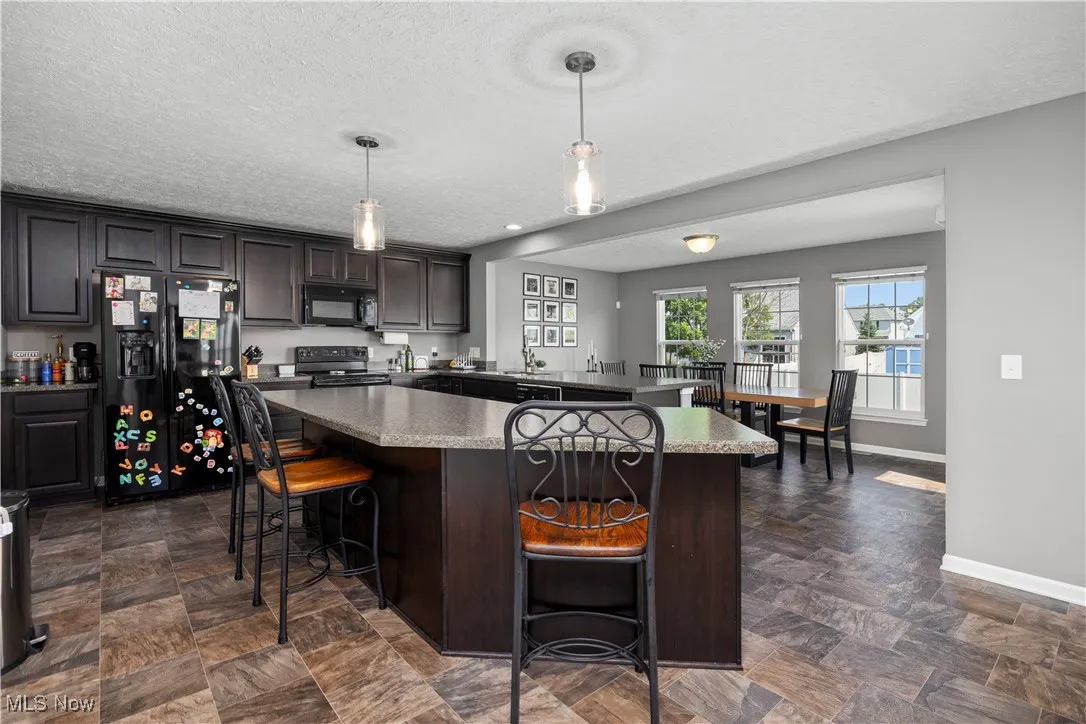Kitchen with black appliances, breakfast bar, kitchen island, and a peninsula with another eating area view faces into morning room and or dining area