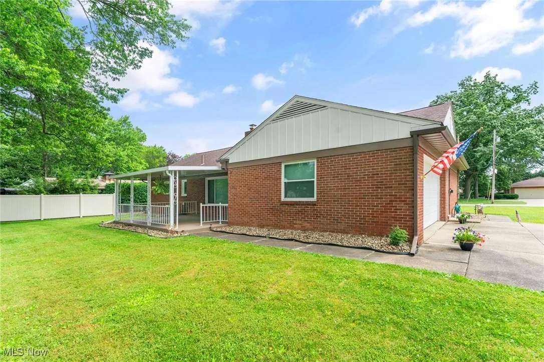 Back of house with brick siding, driveway, a covered porch, and an attached garage
