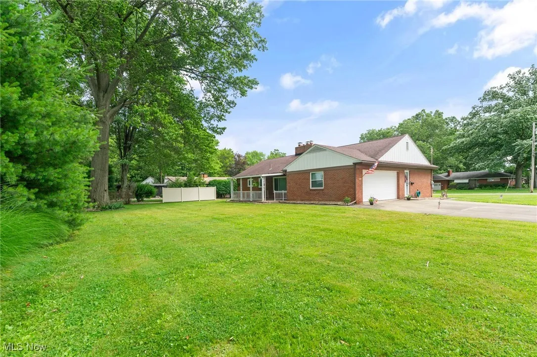 View of back of house featuring concrete driveway, a garage, brick siding, and a chimney