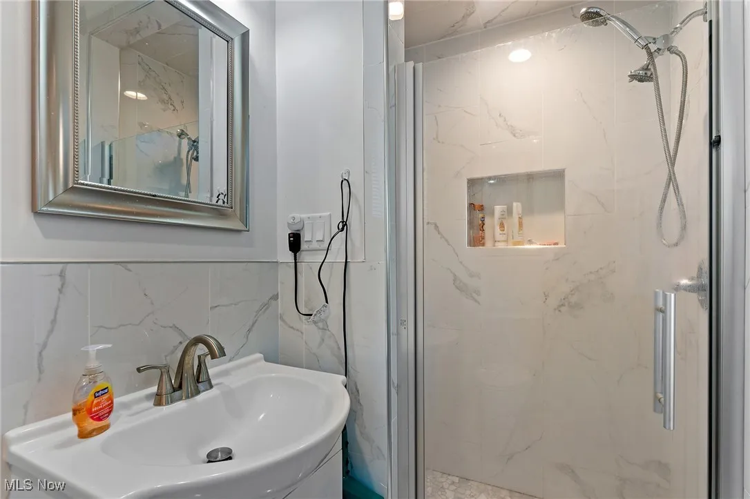 Full bath featuring a marble finish shower and tile walls
