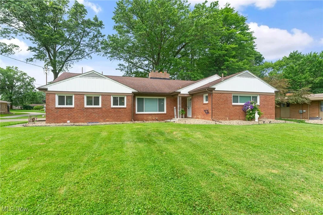 Ranch-style home with brick siding, a front yard, and a chimney