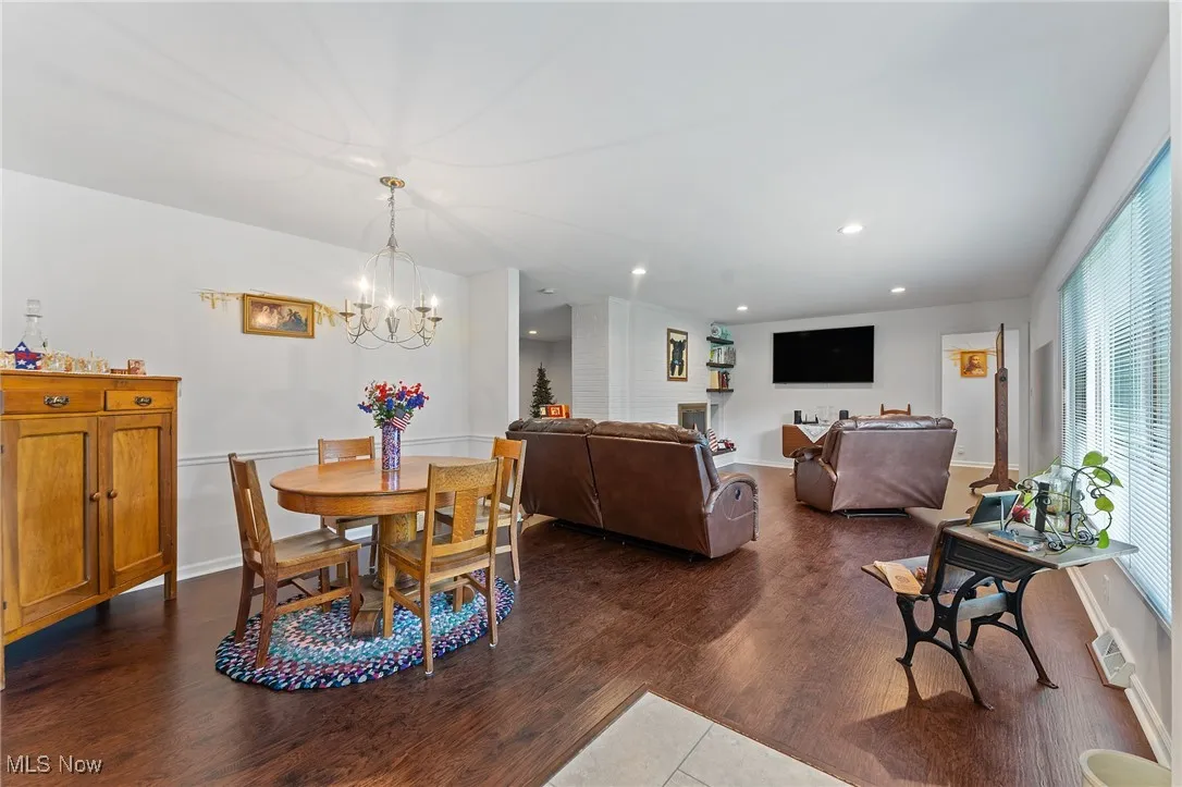 Dining room featuring healthy amount of natural light, a chandelier, dark wood-style flooring, and recessed lighting