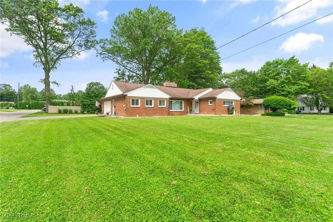 Ranch-style house with a garage, brick siding, driveway, and a front yard.