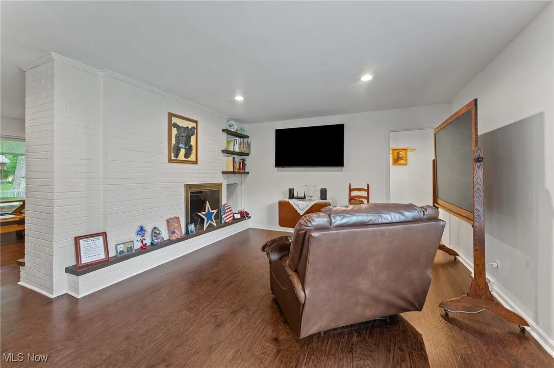 Living room featuring a glass covered fireplace, wood finished floors, and recessed lighting