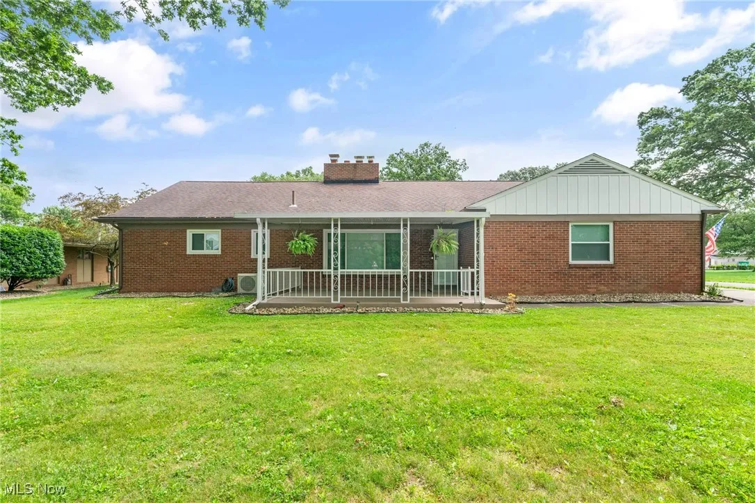 Back of house with brick siding, a chimney, and yard.