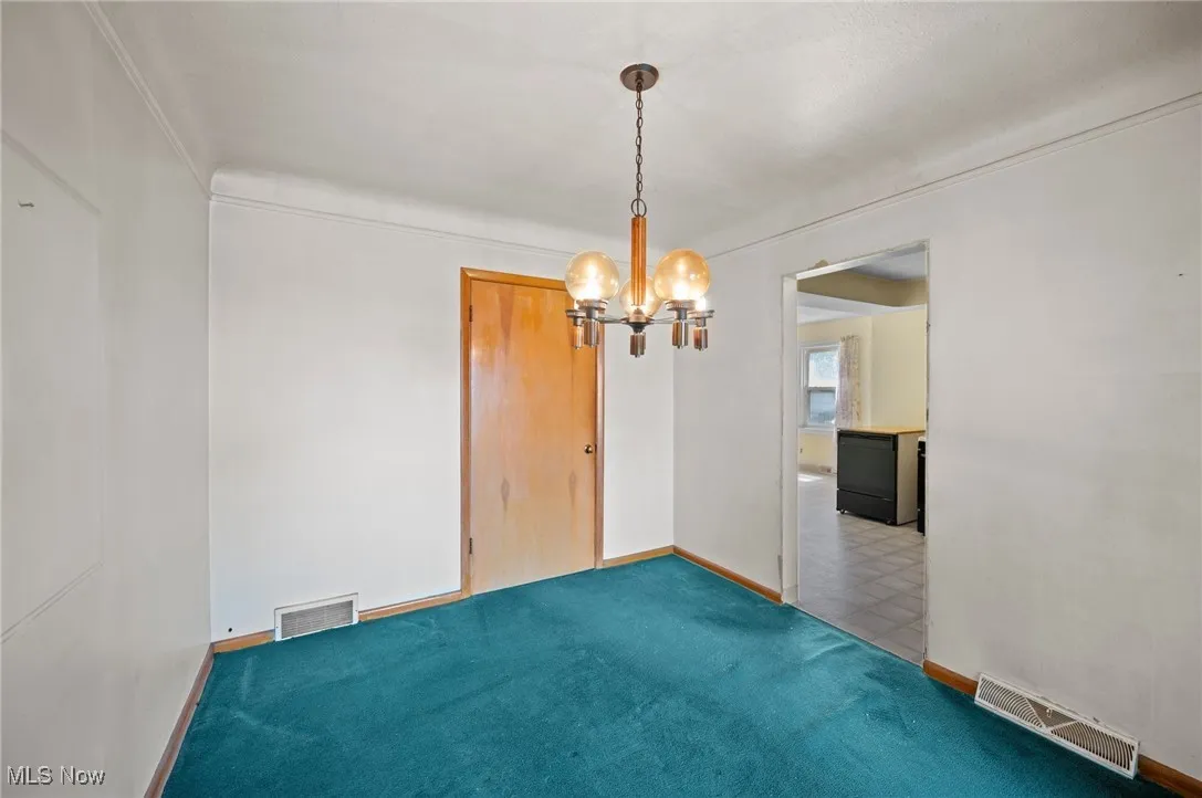 Carpeted dining room featuring a chandelier and baseboards