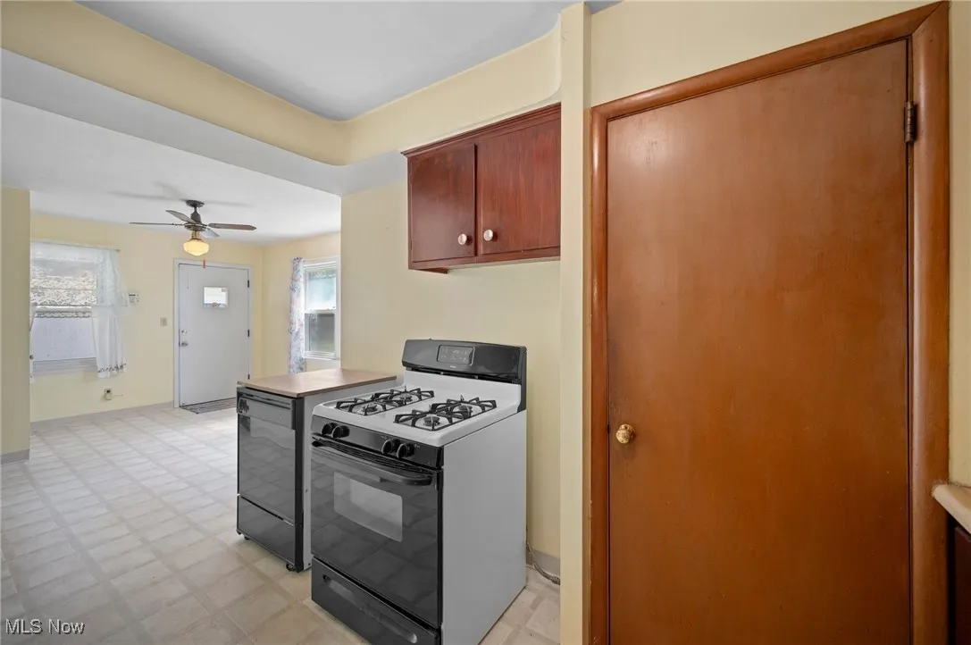 Kitchen with range with gas stovetop, light floors, and brown cabinetry